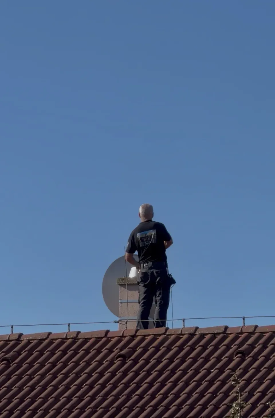 Kominár pri práci na streche rodinného domu